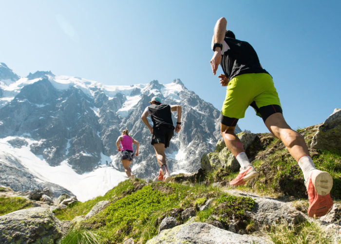 Three trail runners jogging on a mountain trail